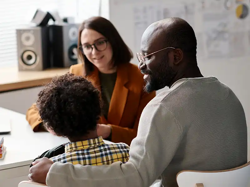 A young person and their parent talking to an adult